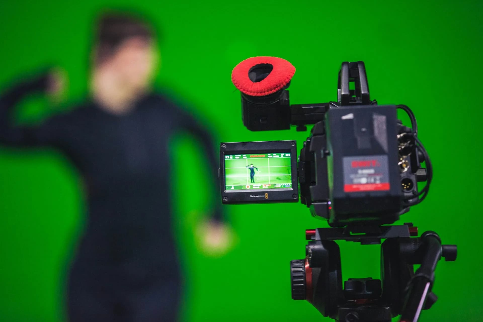 Video camera recording a person in front of a chroma key green screen in a studio