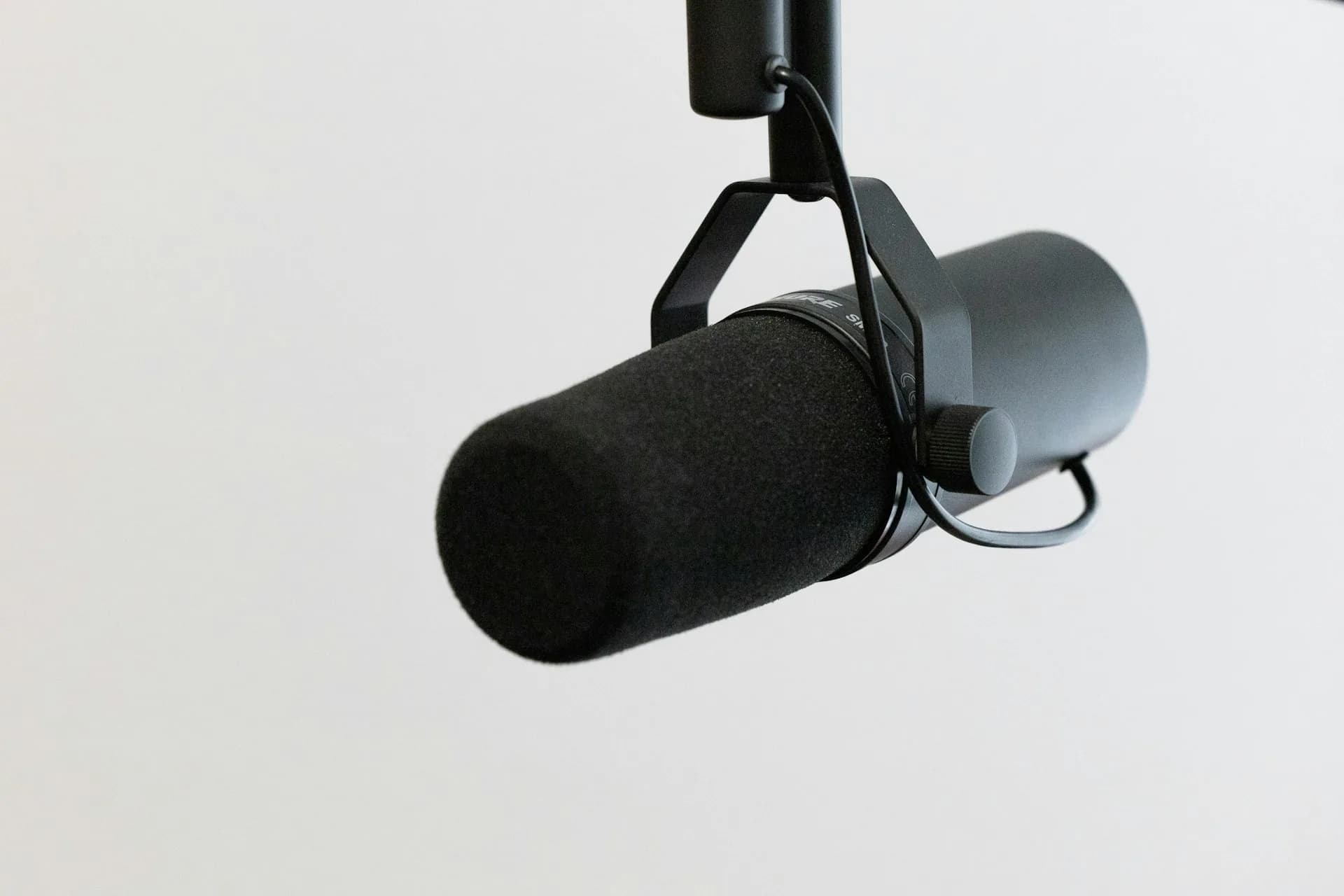 Micrófono de podcast tipo Shure SM7B en primer plano sobre fondo neutro